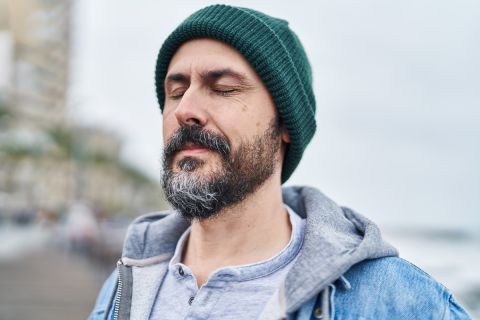 man breathing with closed eyes at seaside